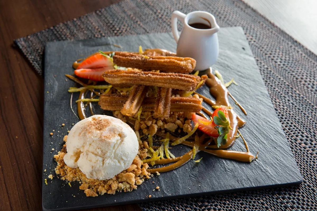 A sobremesa de churros artesanal é harmonizada com calda de doce de leite, nutella, farofa de queijo e sorvete de leite ninho