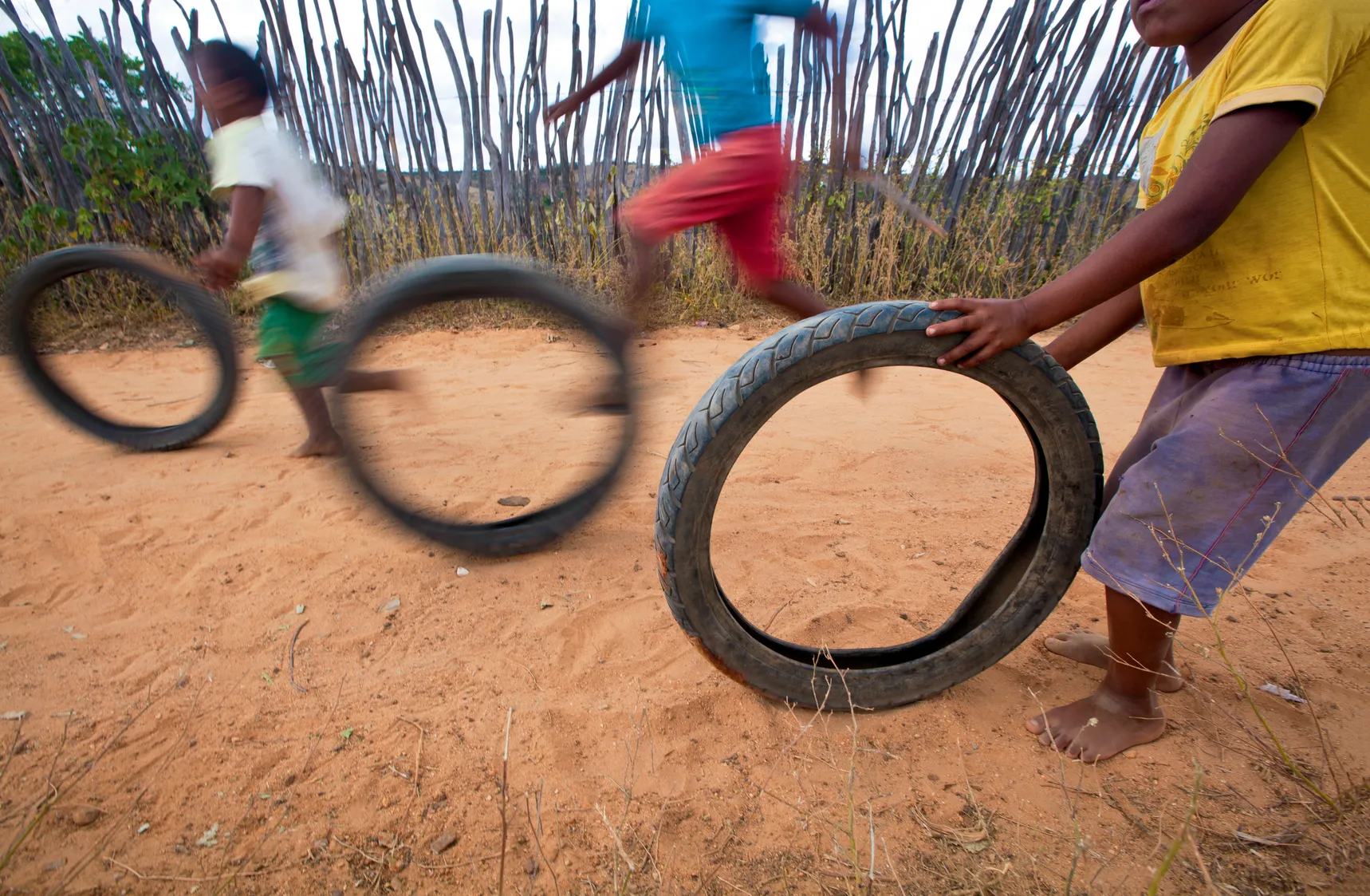 Meninos, soltos feito o vento, brincam com os pés descalços no chão de terra batida. Eles rodam pneus na comunidade Quilombola Carcará, em Potengi, Ceará