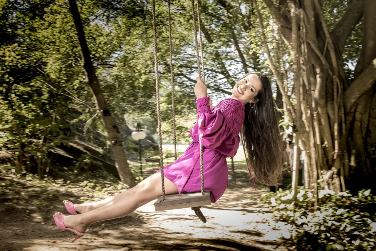 Juliette Freire, participante do BBB21 e ganhadora da edição, sentada em um balanço em um parque com vestido rosa