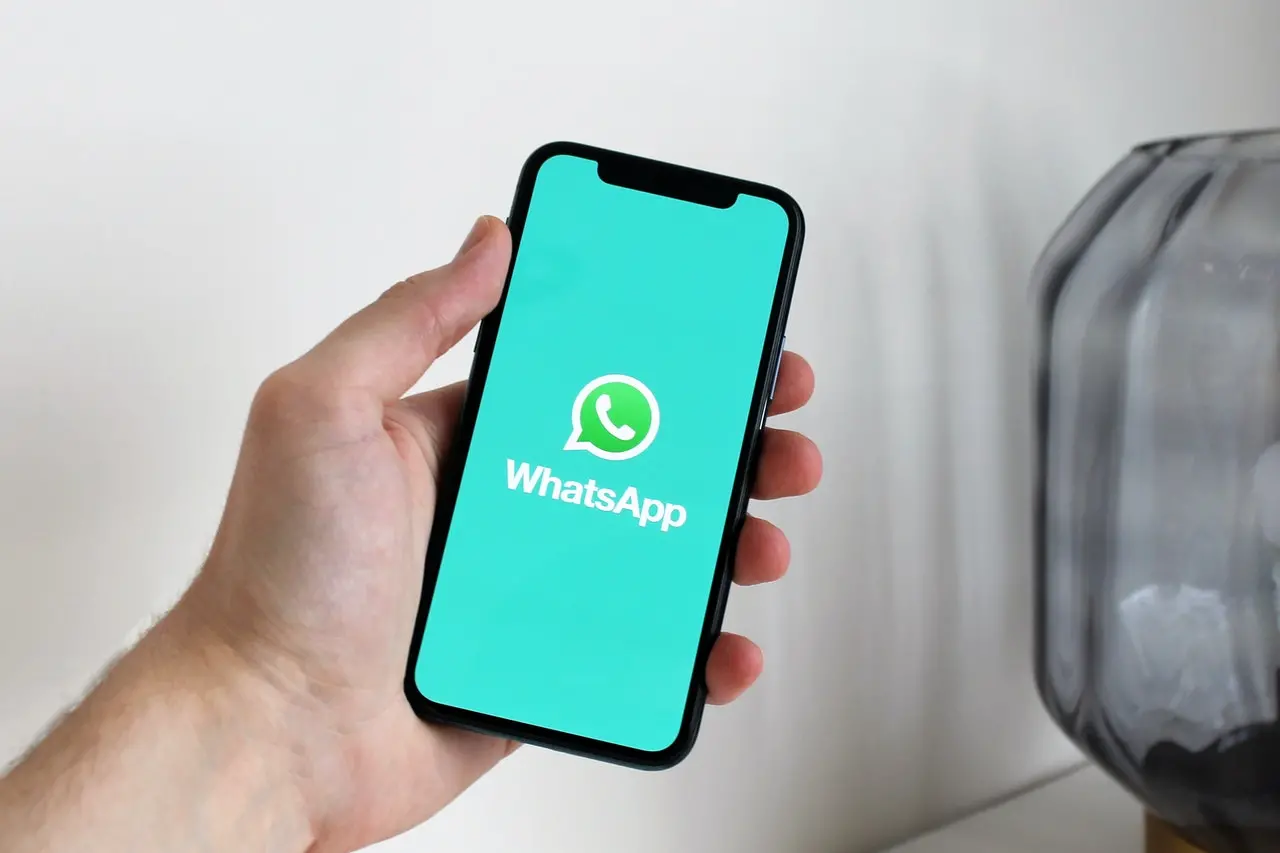 Mão de pessoa segurando o celular com tela do Whatsapp