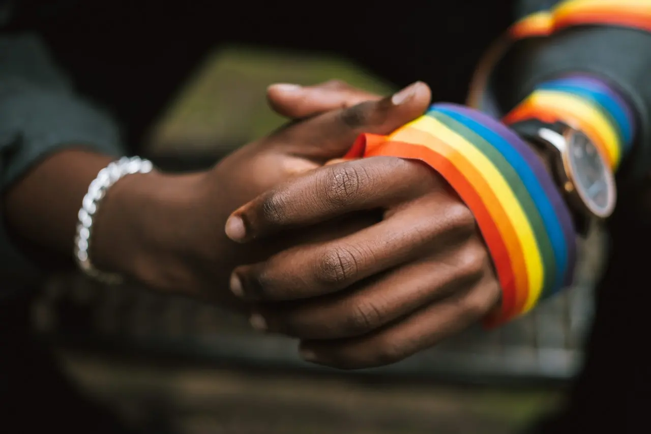 Mãos negras com faixa com cores do arco-íris na mão
