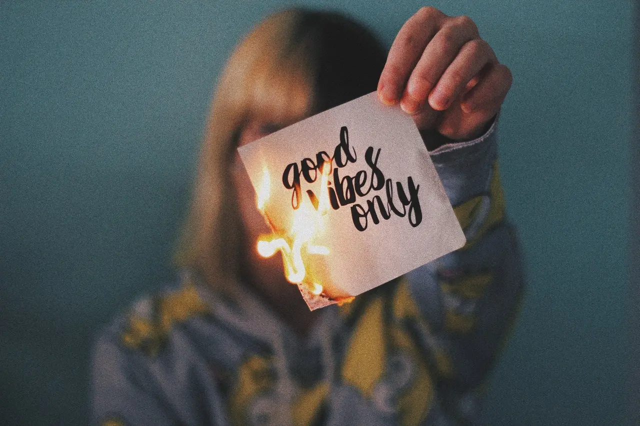 pessoa queimando papel com a frase good vibes only