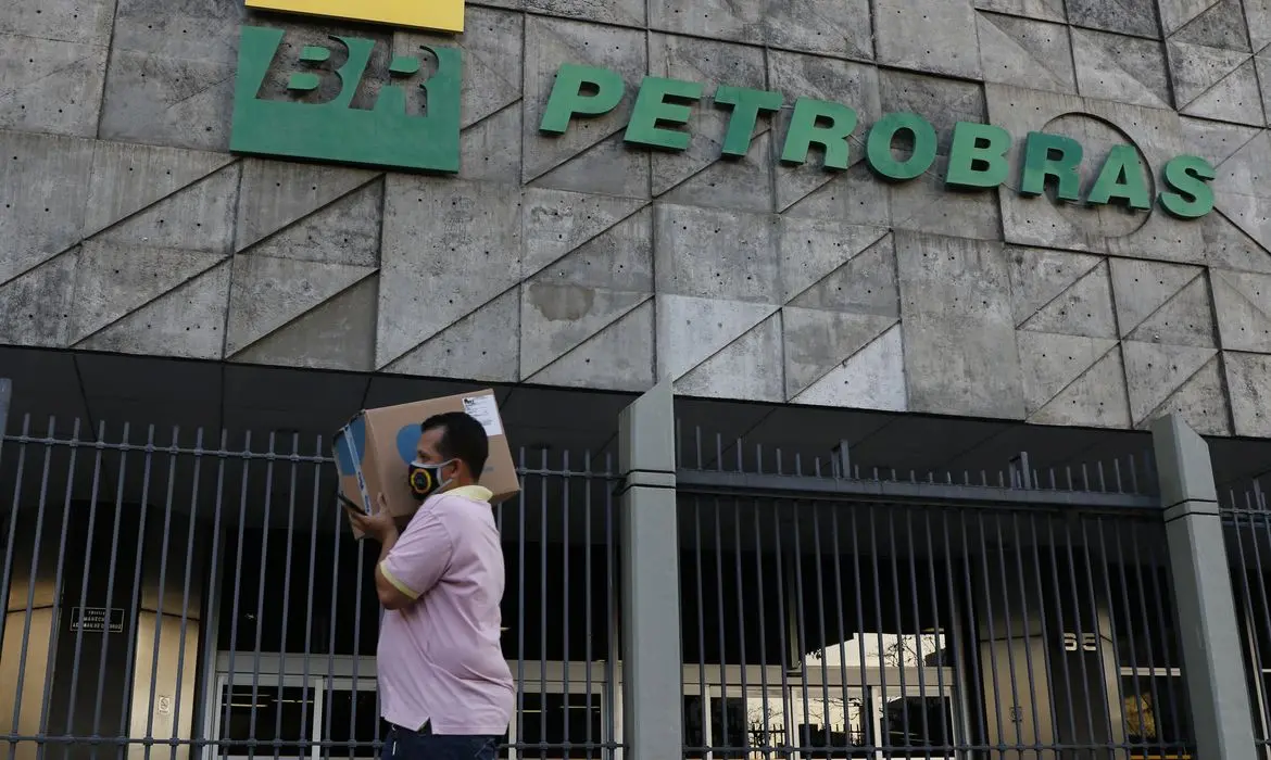 Homem carregando caixa passando em frente à fachada da Petrobras