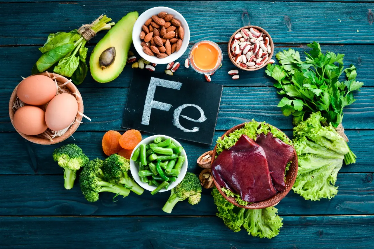 Alimentos ricos em ferro disposto em uma mesa com uma placa com o nome do elemento 