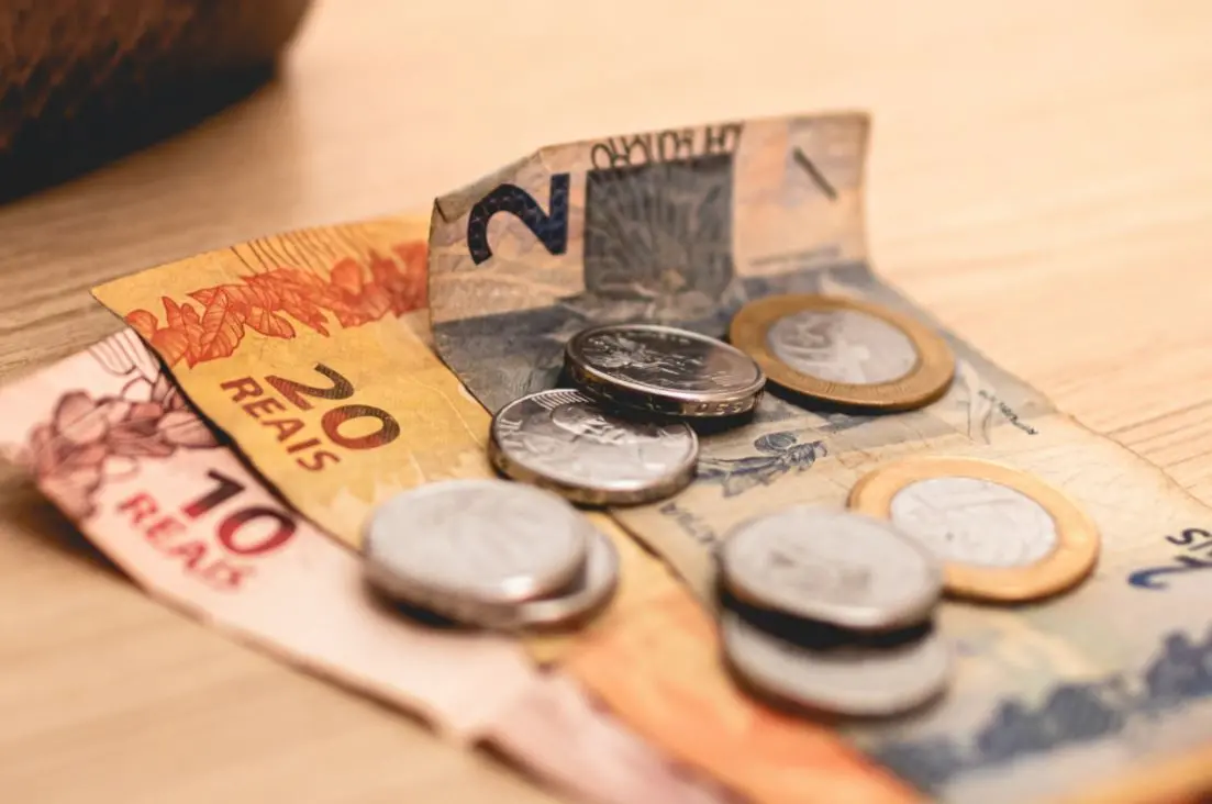 Cédulas e moedas de real em cima de superfície de mesa
