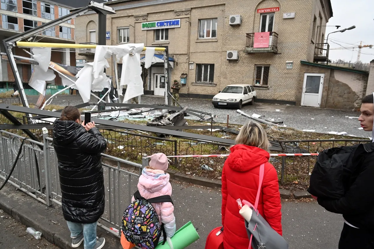 Pessoas são vistas fora da área isolada ao redor dos restos de um projétil em uma rua em Kiev, em 24 de fevereiro de 2022. O presidente russo, Vladimir Putin, anunciou uma operação militar na Ucrânia.
