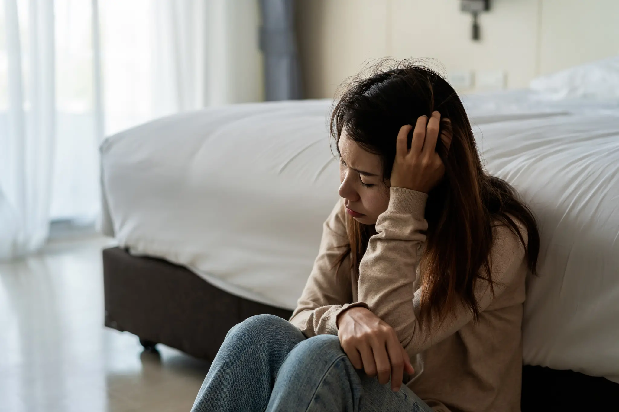 Mulher cansada sentada ao lado da cama