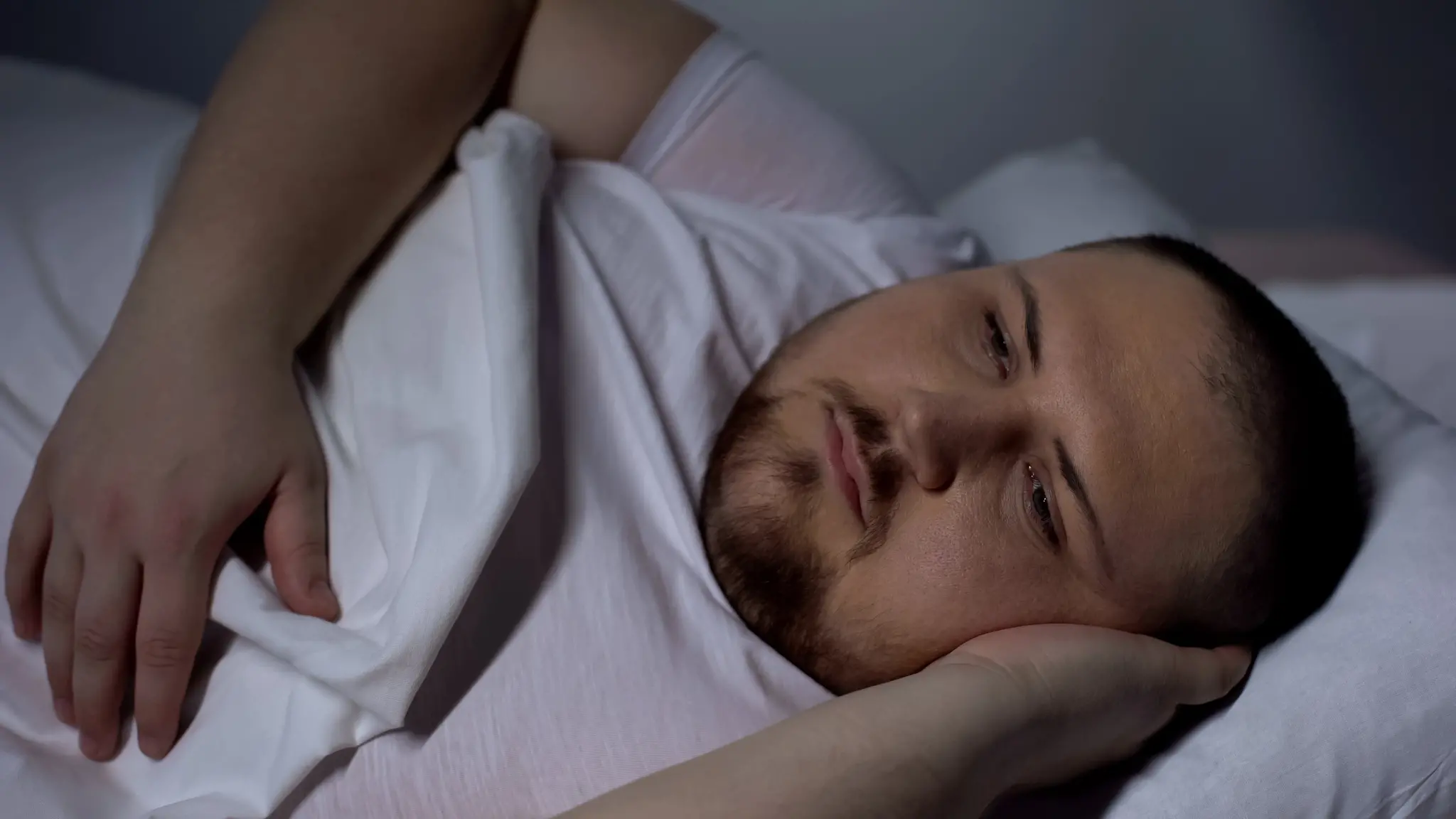Homem sem dormir deitado em uma cama