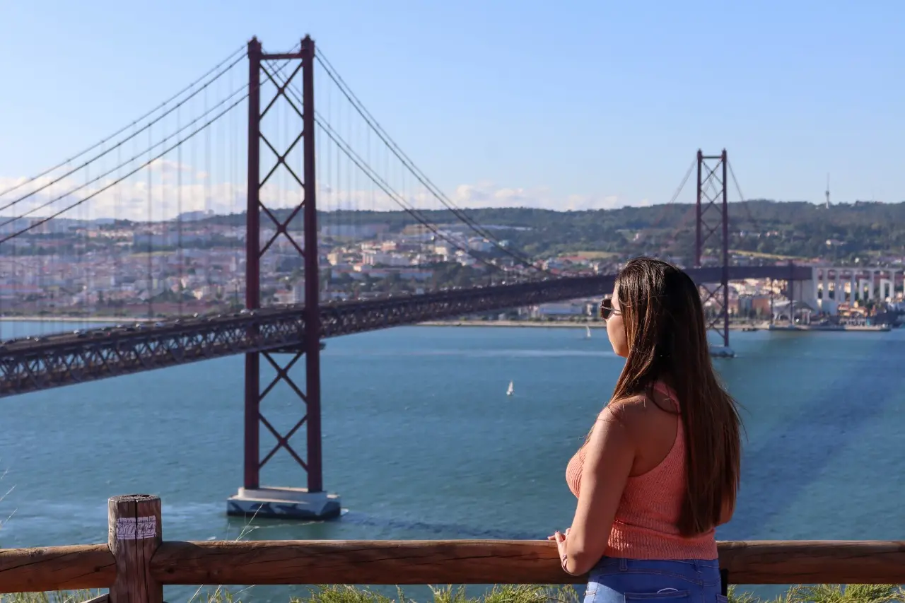 Mulher olha para ponte em Lisboa, Portugal