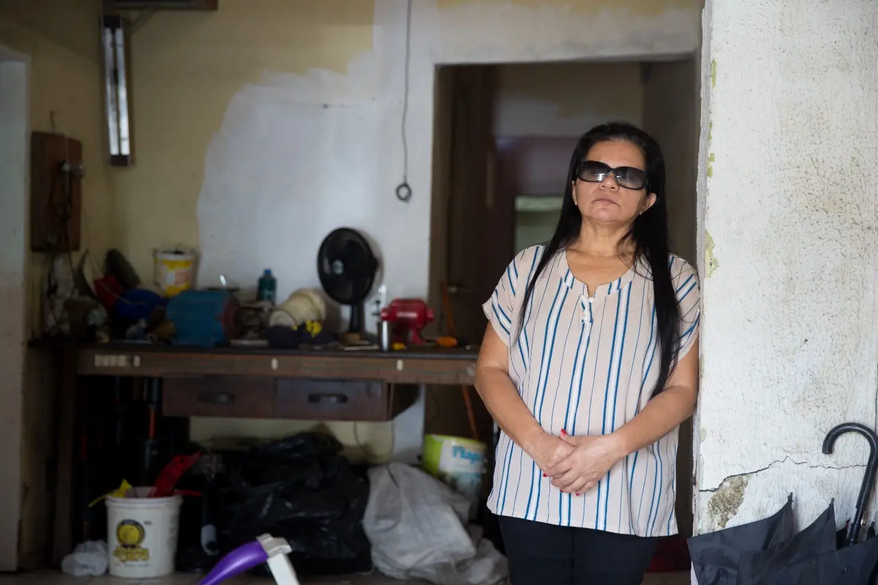 Personagem de óculos escuro encostada em um muro