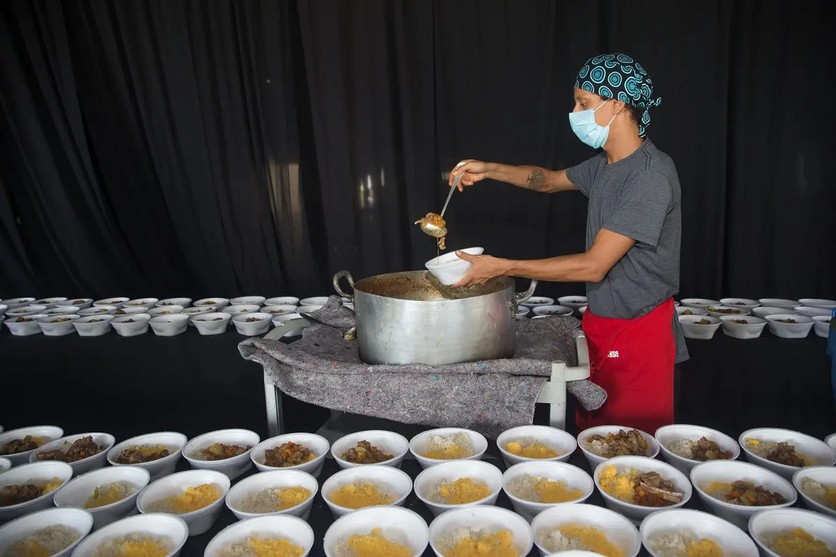 pessoa coloca comida em marmitas