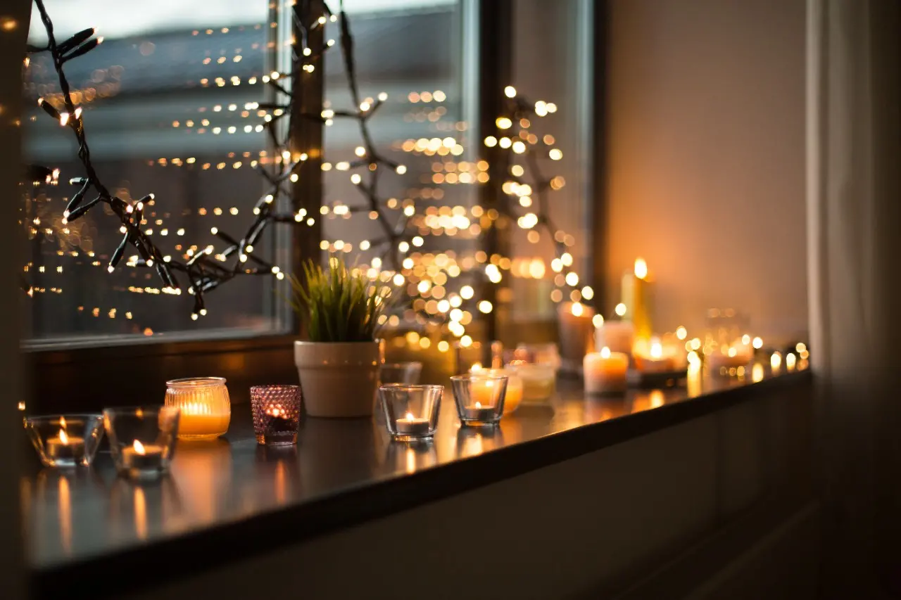 Iluminação com luzes de natal e velas próximo a janela