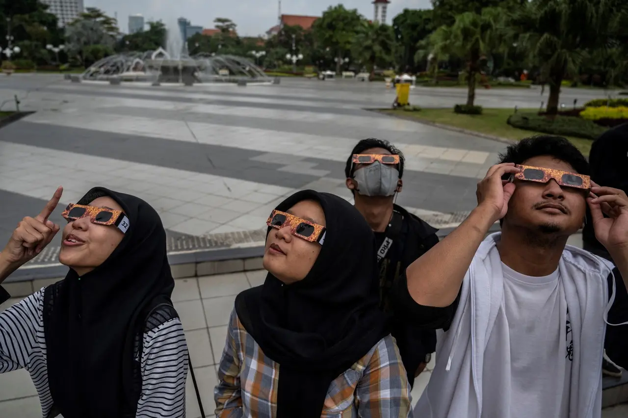Pessoas assistem eclipse solar híbrido raro registrado entre 19 e 20 de abril de 2023 na Indonésia