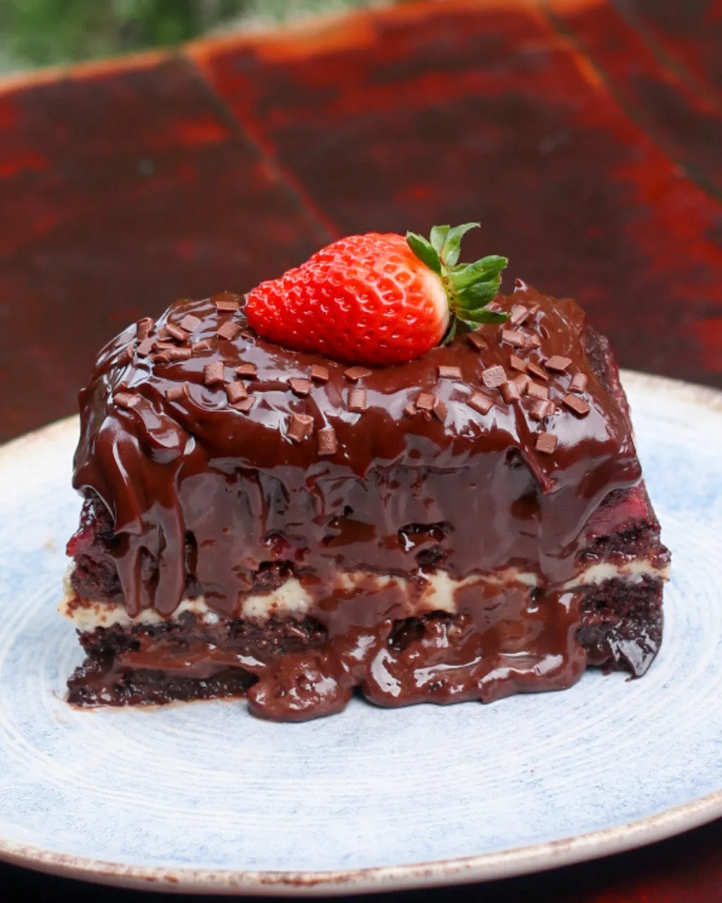 Mega Fatia Trino é uma torta feita com massa especial de cacau e recheio de brigadeiro de Ninho, brigadeiro de Chocolate e geleia artesanal de morango