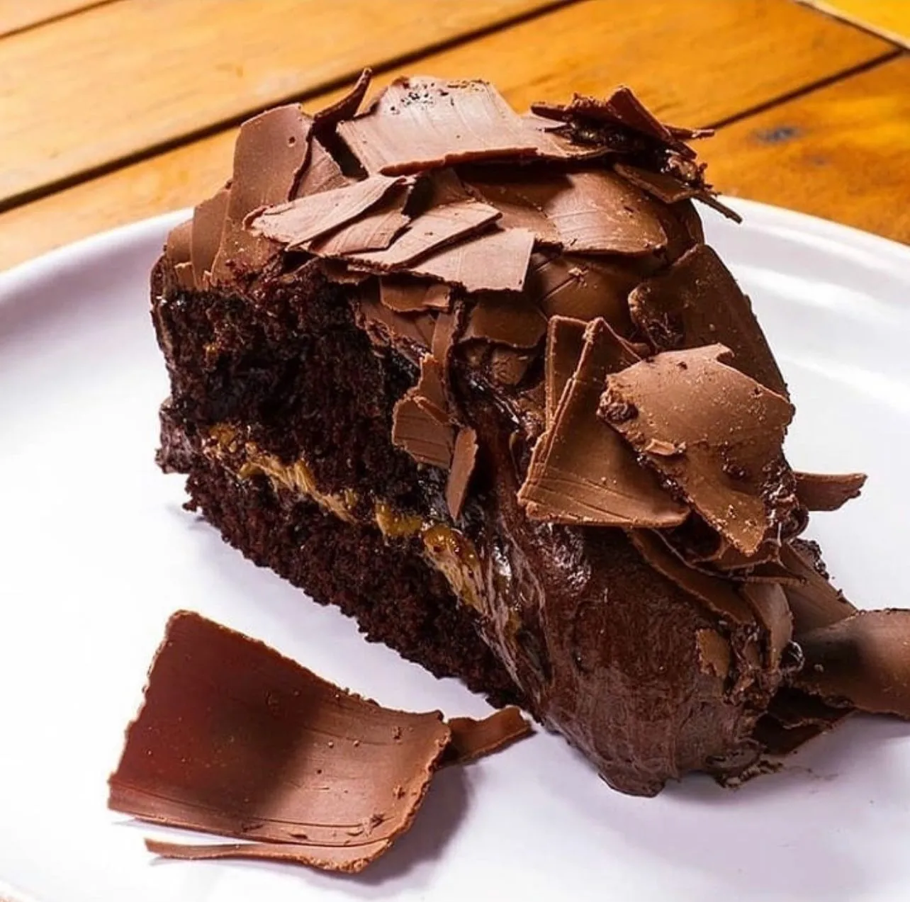 Clássica torta Xuxa, com massa de chocolate molhada, recheio de doce de leite, com cobertura especial de chocolate e muitas raspinhas de chocolate ao leite