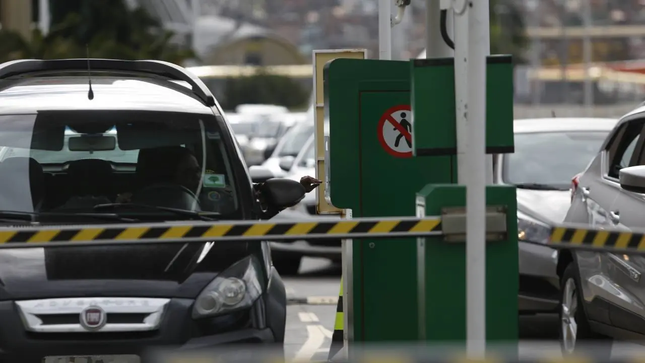 Homem em carro passa por cancela de estacionamento
