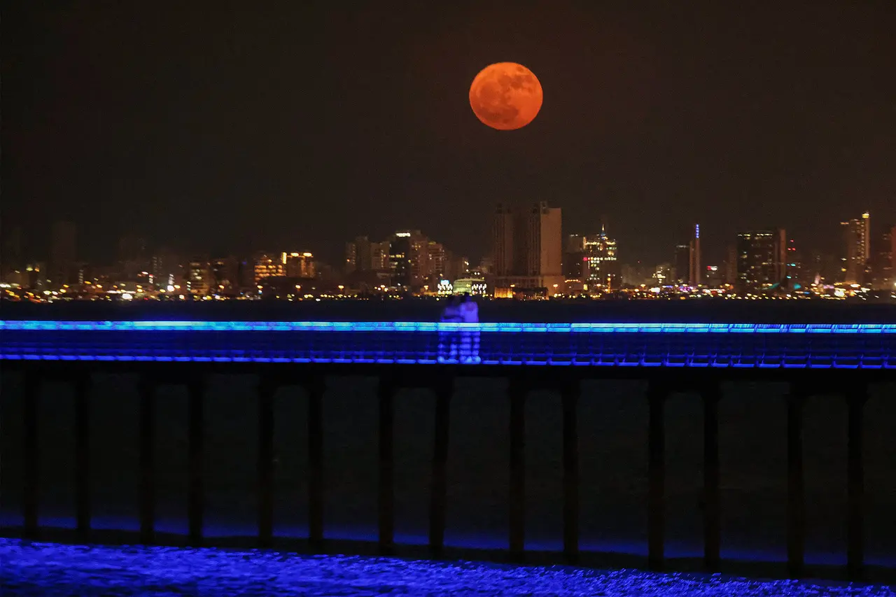 Pessoas observam a 'Superlua dos Cervos' surgir no horizonte da cidade do Kuwait em 3 de julho de 2023.