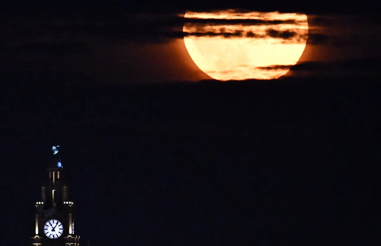 'Superlua dos Cervos' surge entre as nuvens atrás do Edifício Liver em Liverpool, noroeste da Inglaterra, no final de 3 de julho de 2023.
