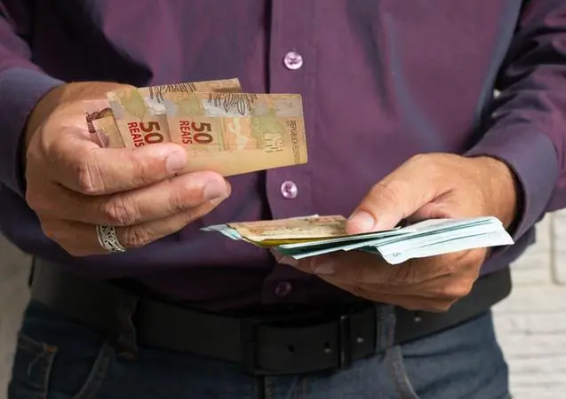 Homem contando cédulas de Real