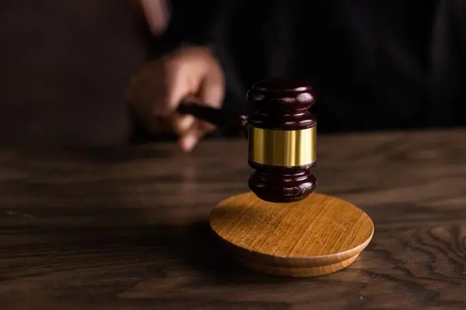 Mão segurando martelo de juiz sobre uma mesa
