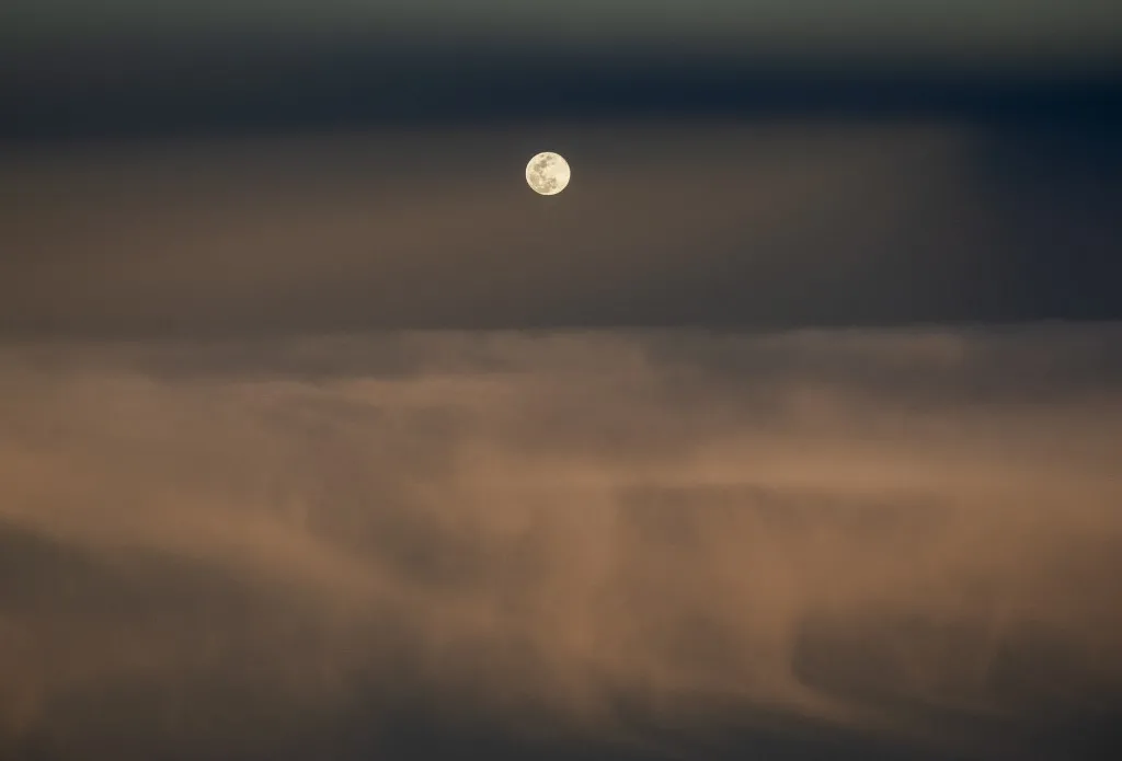 A lua através de uma tempestade de poeira na costa do Saara Ocidental, vista de um avião