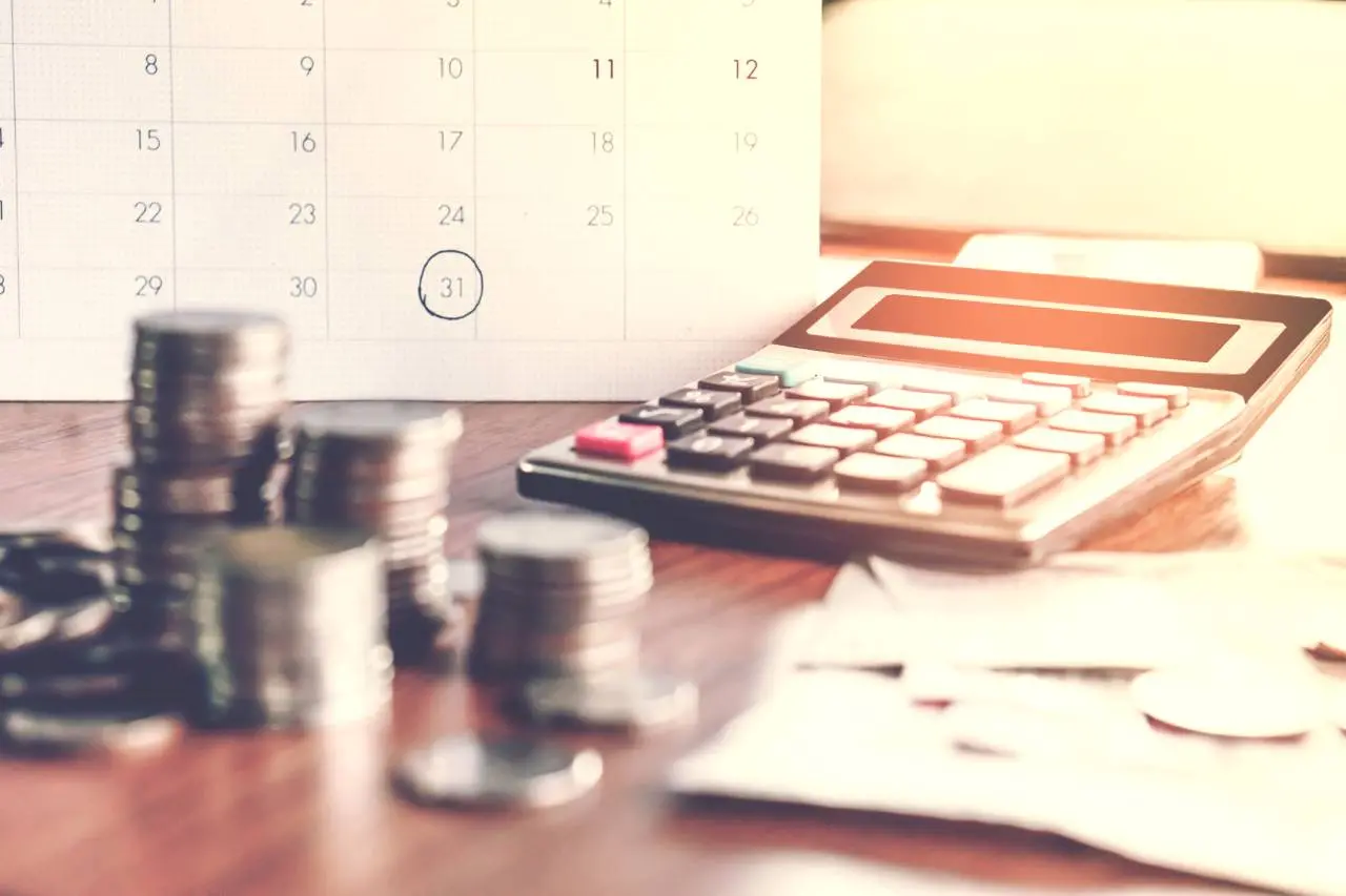 Moedas e calculadora sobre mesa