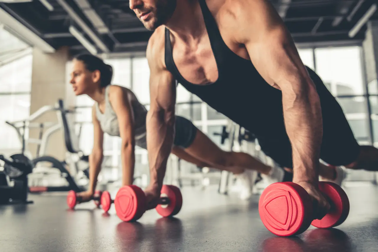 Imagem mostra homem e mulher se exercitando em academia, focando em músculo. Saiba o que é albumina e se ela é melhor que whey protein para ganho de massa muscular