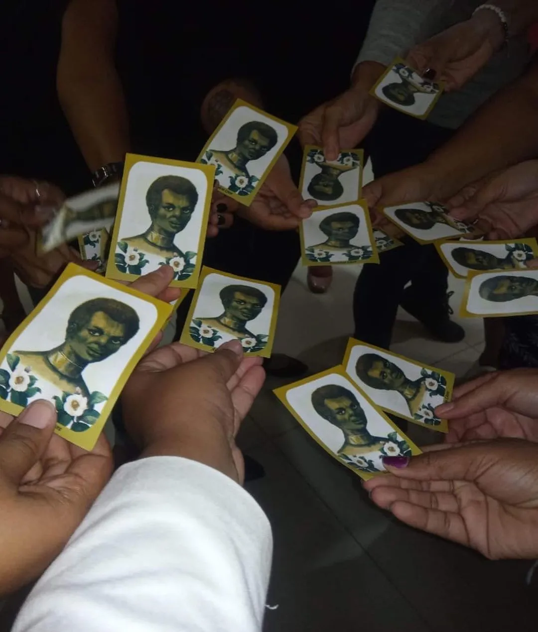 Hoje, guardo um santinho na carteira. Ele projeta o rosto de uma mulher negra enfeitada de bromélias