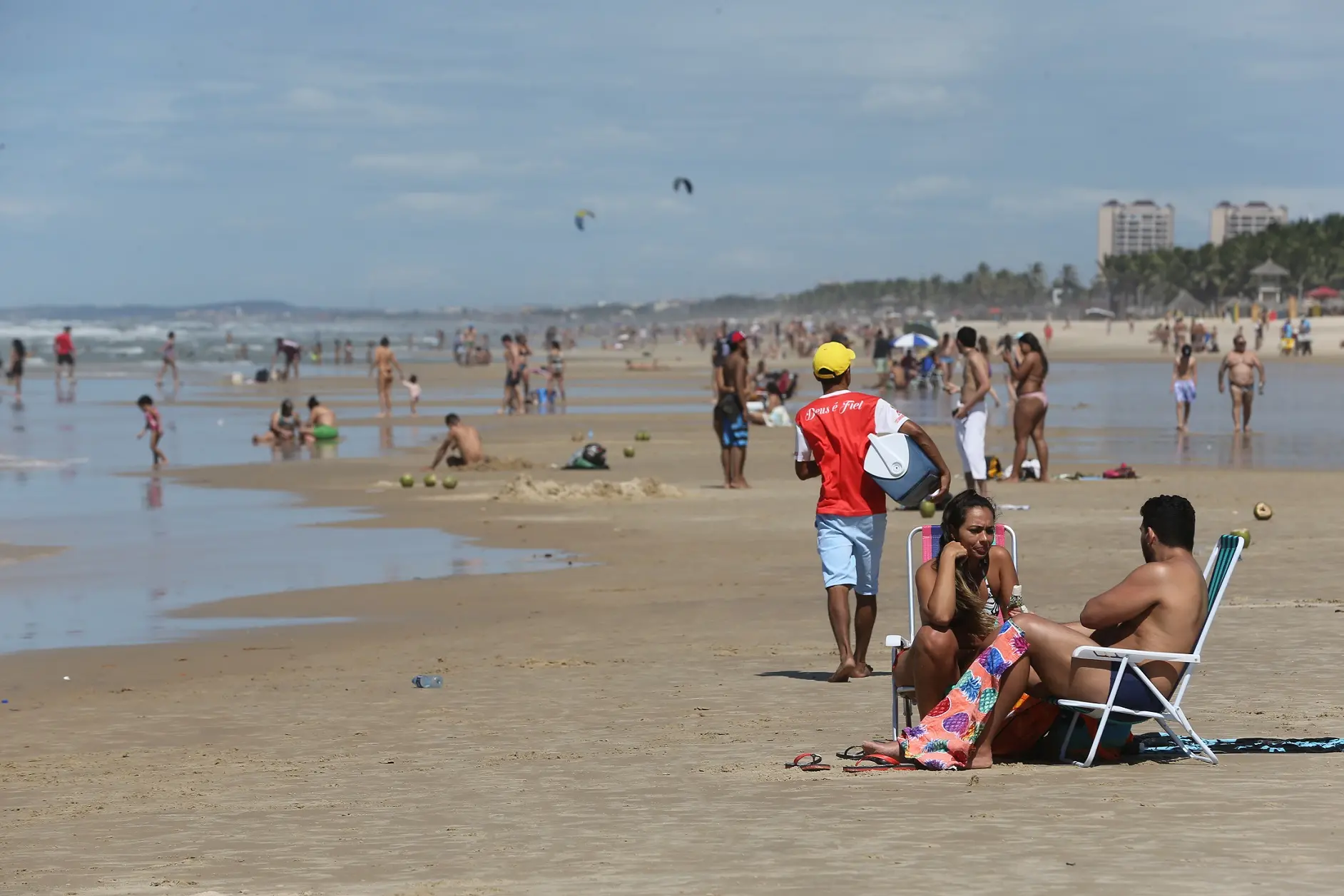 Pessoas na areia da praia, foco em um homem brincando com uma criança