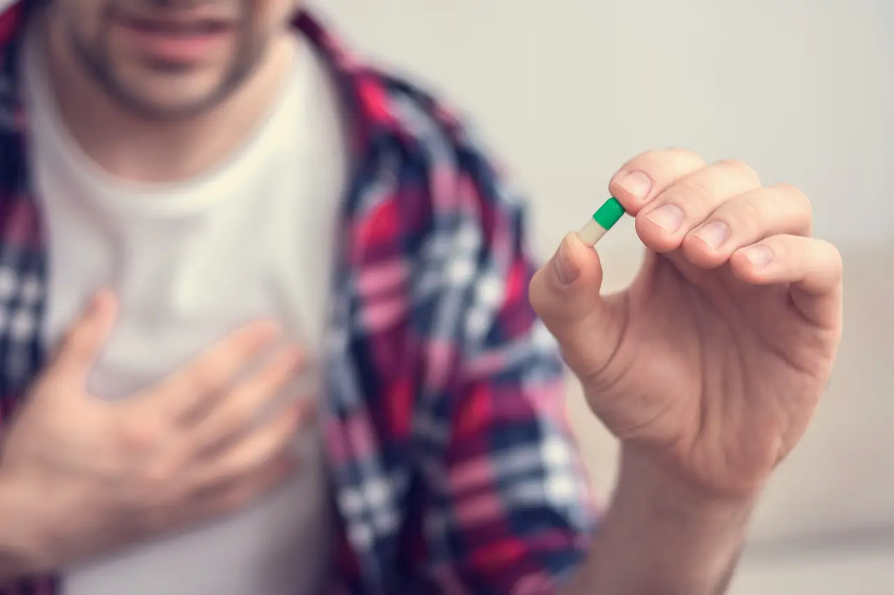 Homem com mão no peito segura comprimido. Tratamento para tipo de insuficiência cardíaca ganha nova opção de medicamento no Brasil