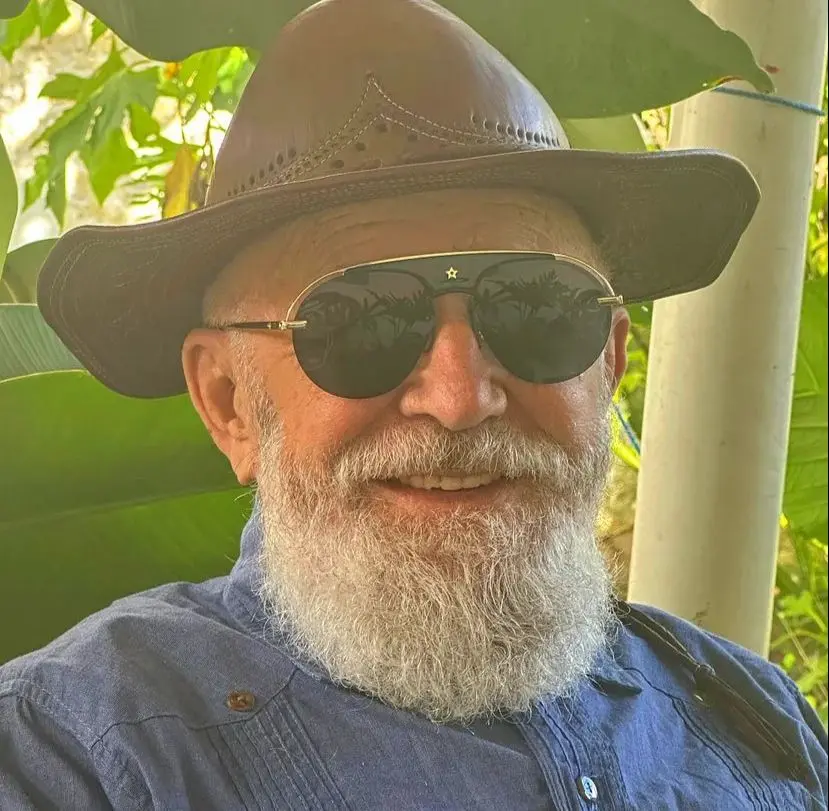 Biliu de Campina é um homem branco idoso de barba branca espessa e, na foto, está de óculos escuros estilo aviador e chapéu de couro