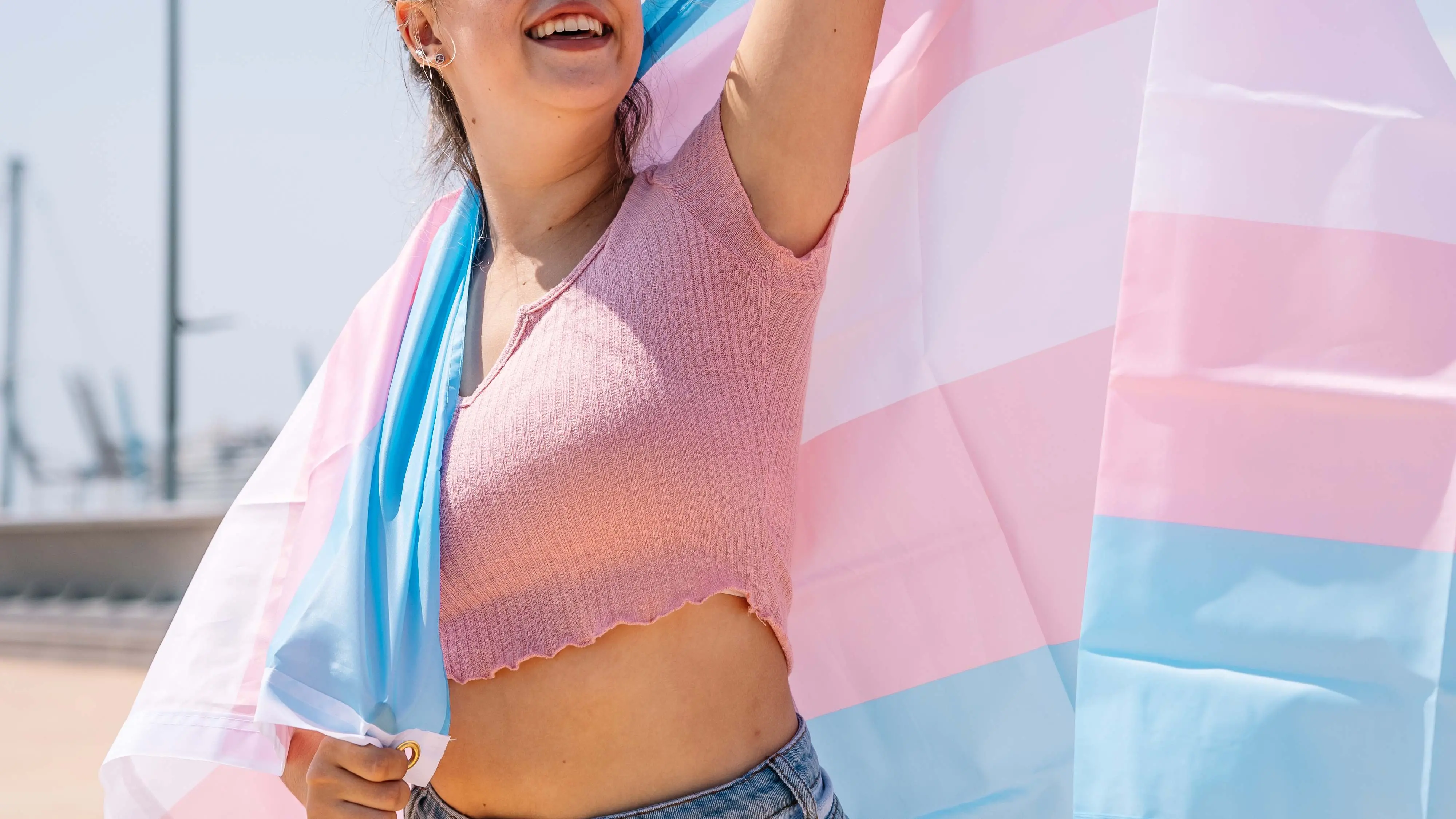 Mulher transexual segura bandeira que simboliza a população trans