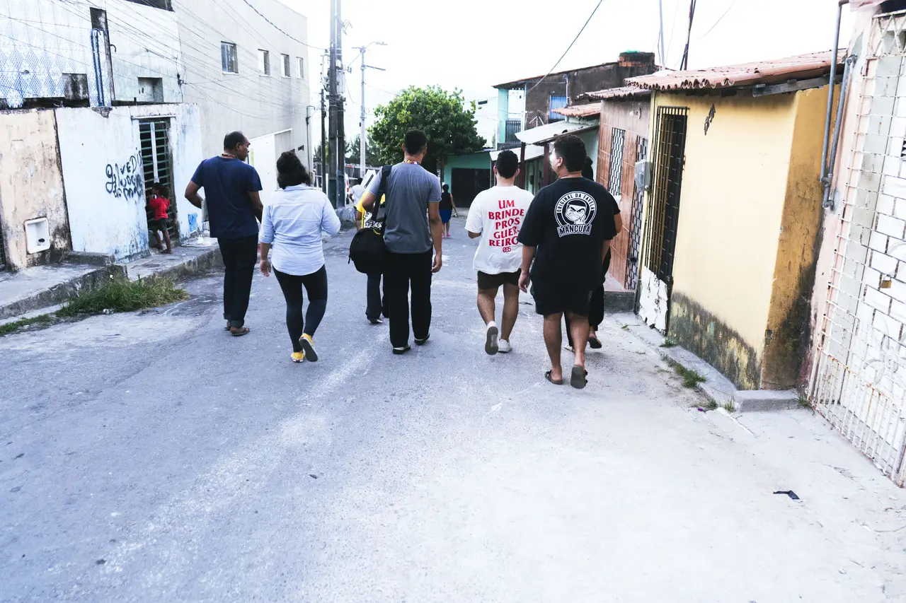Grupo de pessoas de costas caminhando pelo bairro Moura Brasil