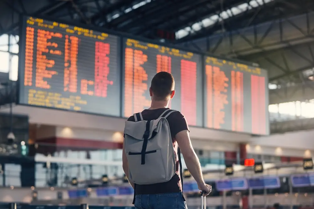 Homem olhando para painel de voos em aeroporto