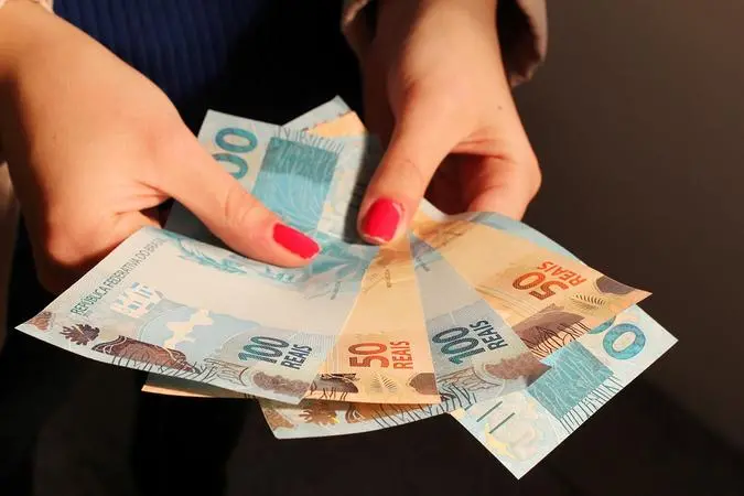 pessoa segurando notas de 50 e 100 reais