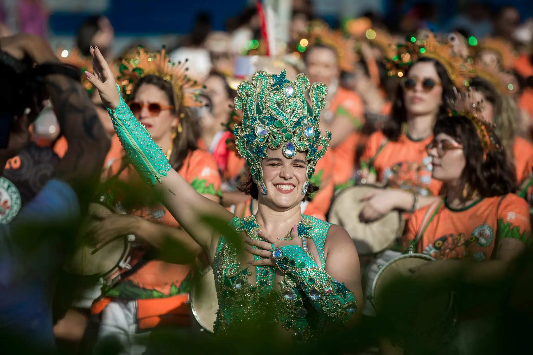 Mulher fantasiada e sorrindo, em meio a bloco de pré-carnaval