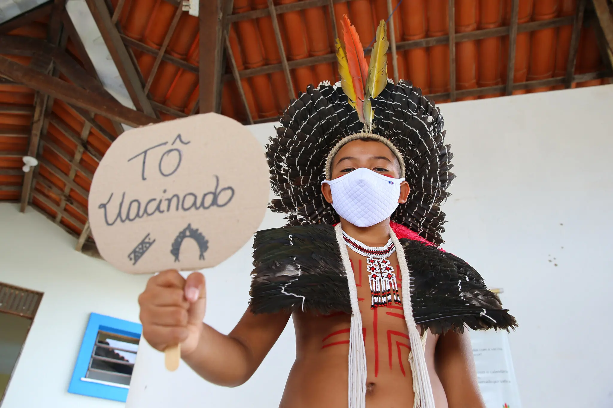 Criança indígena segura cartaz em que está escrito 
