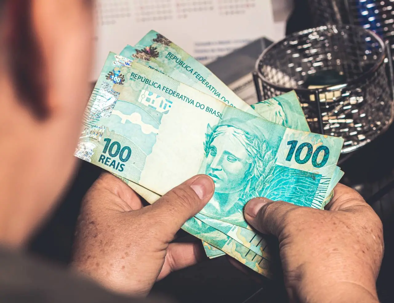Homem segura notas de R$ 100,00