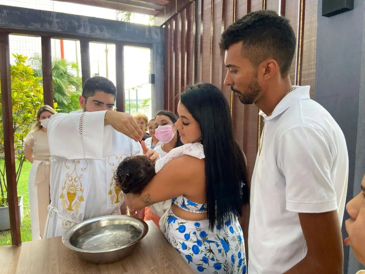 Imagem mostra padre batizando bebê em colo da mãe e ao lado do pai em cerimônia de batizado realizado no hospital Infantil Albert Sabin (Hias), localizado em Fortaleza. Bebê internada há meses ganha cerimônia de batizado em hospital público de Fortaleza