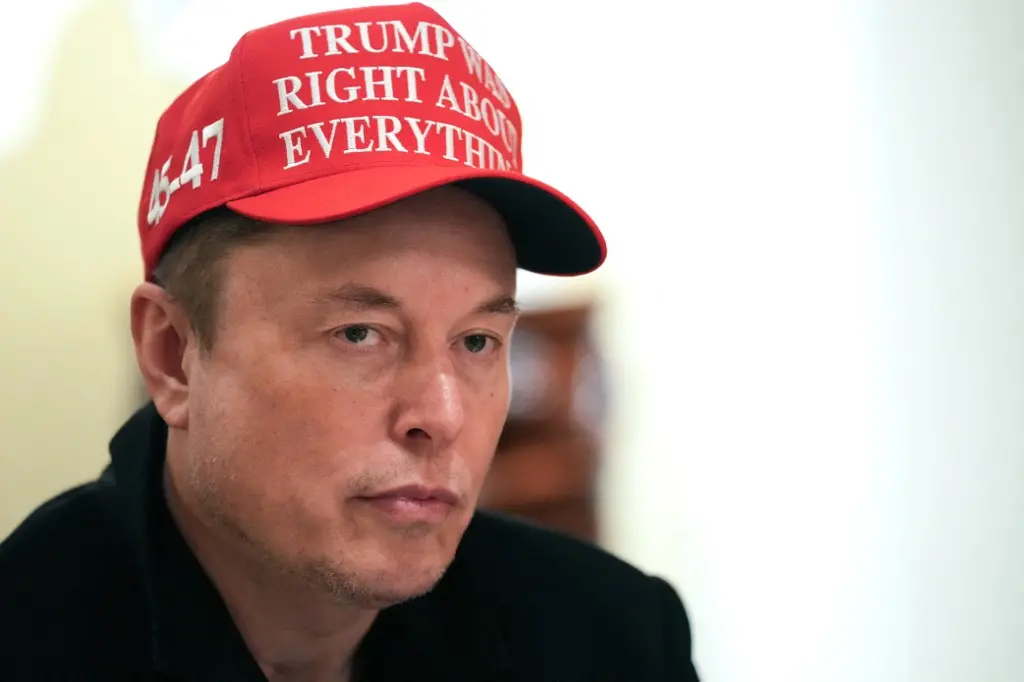 Elon Musk usando um boné vermelho com a frase 'Trump was right about everything'. Ele é um conhecido empresário e inovador tecnológico.