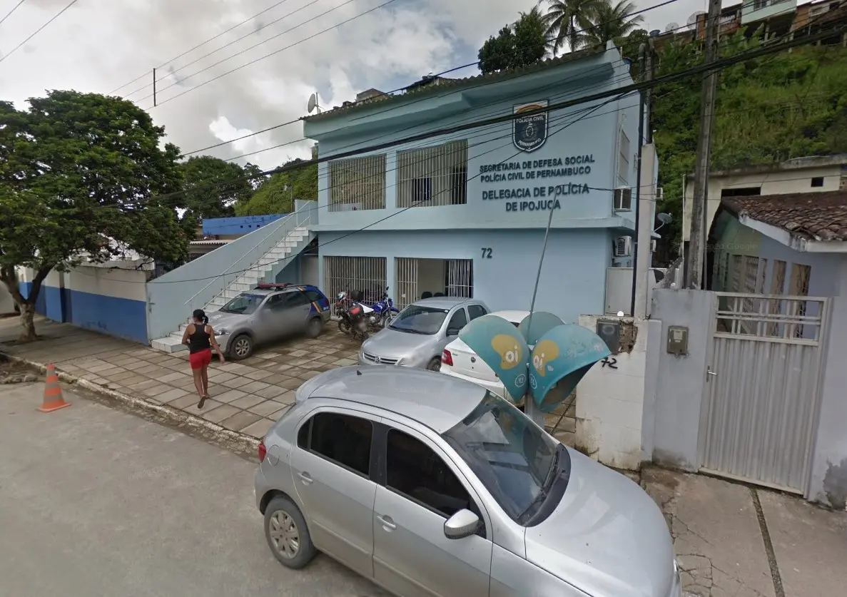 Imagem da Delegacia de Polícia de Ipojuca, localizada em Pernambuco, destacando a fachada do prédio e veículos estacionados.
