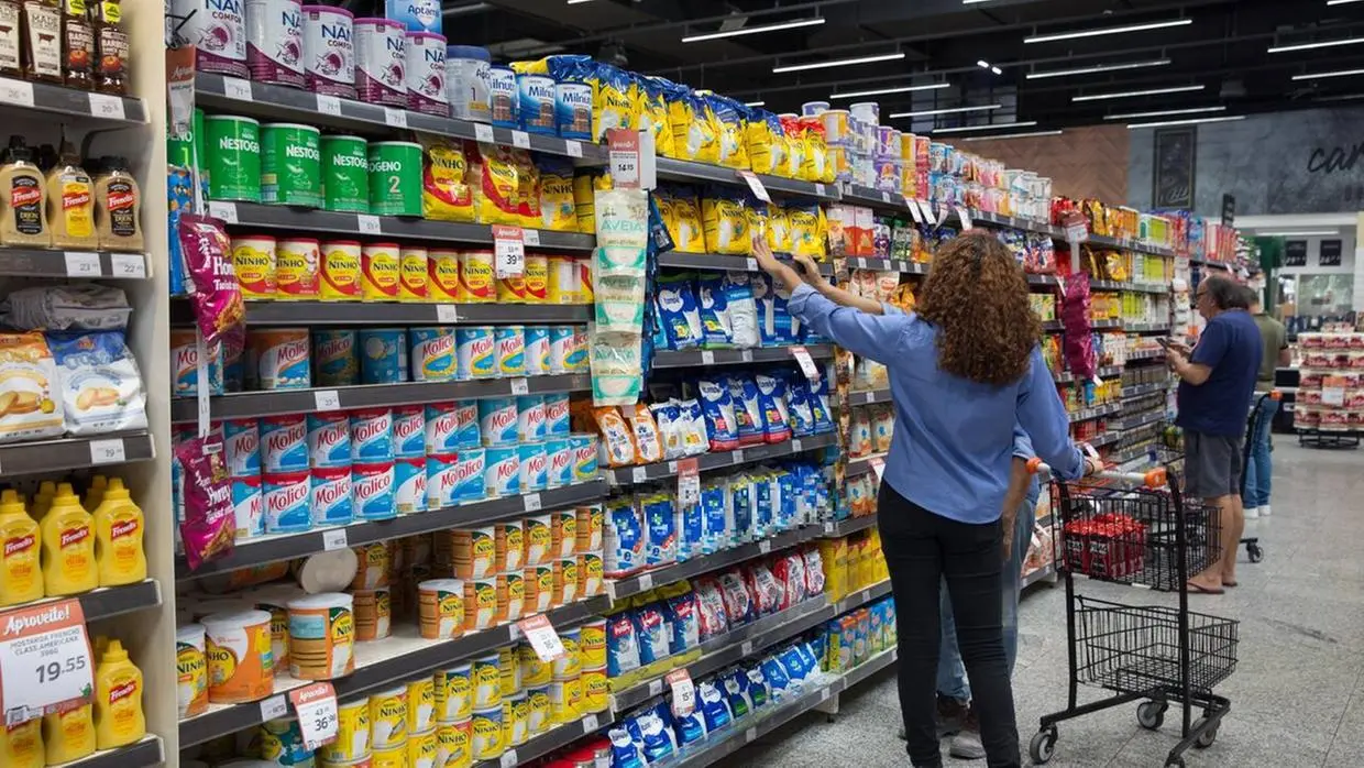 Imagem mostra consumidores uma seção de leites e derivados no supermercado