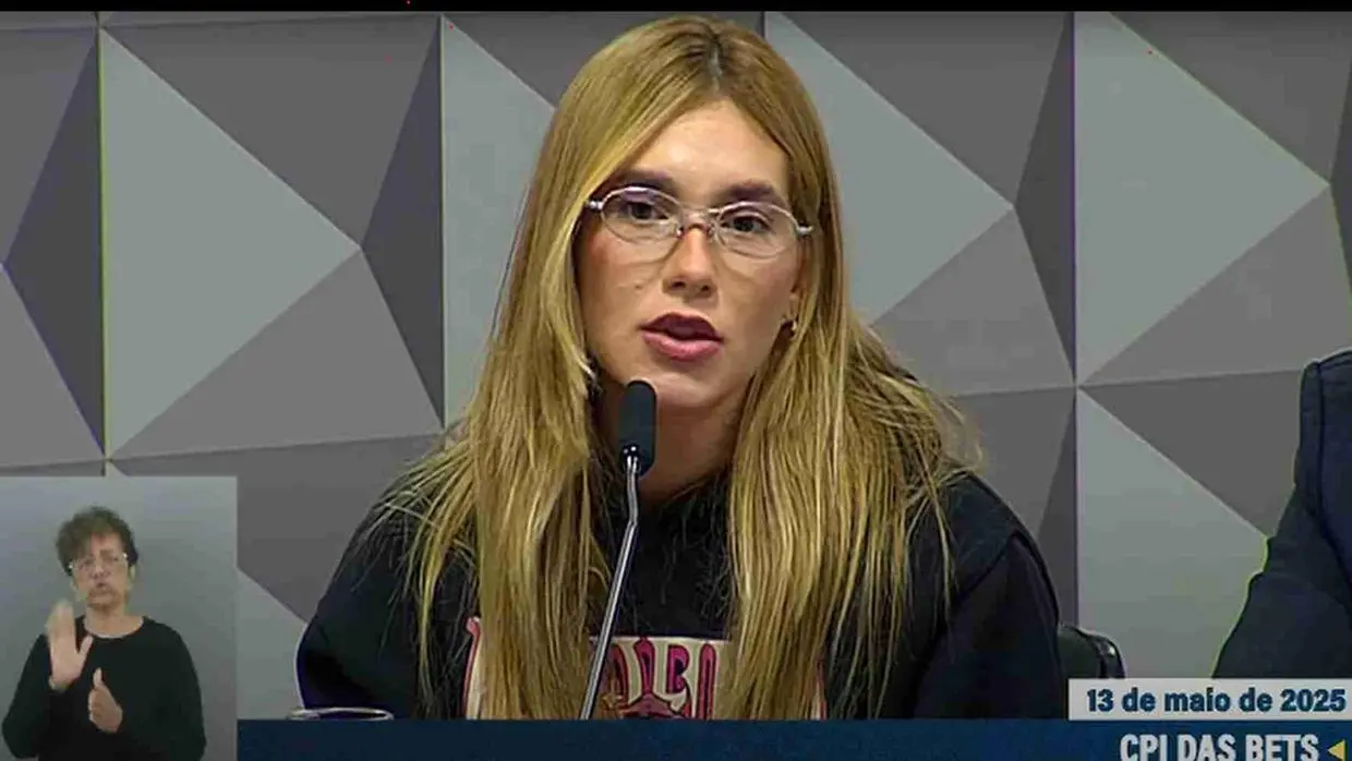 Virgínia Fonseca, mulher branca de cabelos longos louros, com blusa escura falando ao microfone