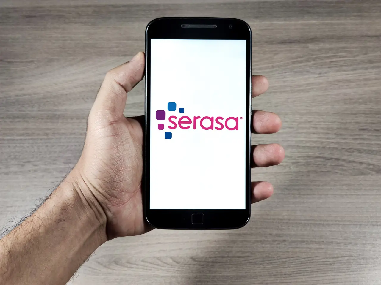 consumidor segurando o celular com o aplicativo da serasa com o objetivo de consultar o score de crédito