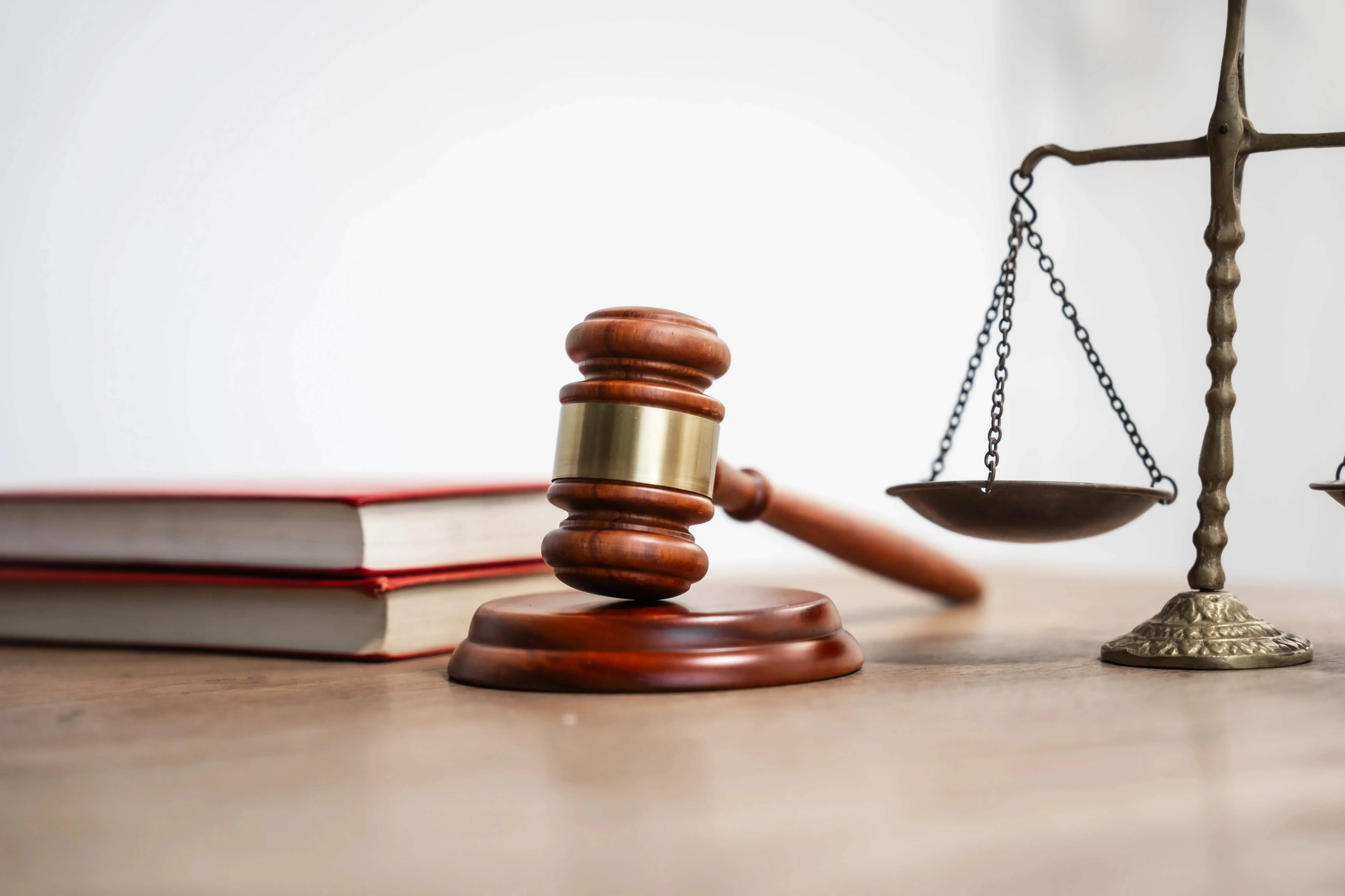 Imagem de um martelo de juiz, uma balança de justiça e livros jurídicos, simbolizando o tema de ética na advocacia e direito, que representa a decisão de indenizar em R$ 120 mil uma aluna que sofreu lesão permanente em aula prática.