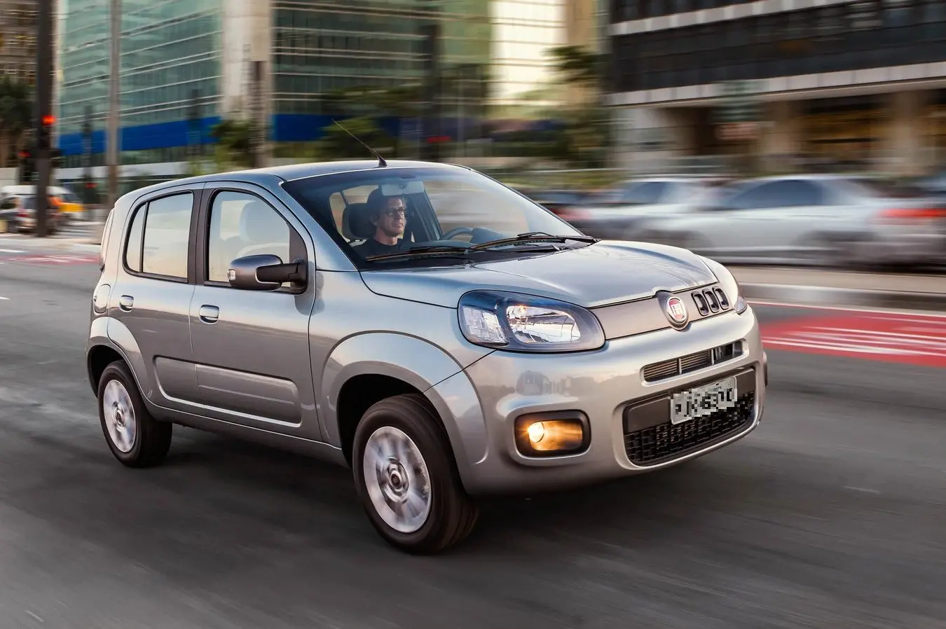 Na imagem, um homem dirige um Fiat Uno na cor prata
