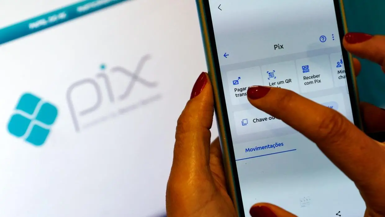 pessoa clica na palavra pix em tela do celular. ao fundo, logo do pix. pix automático é lançado
