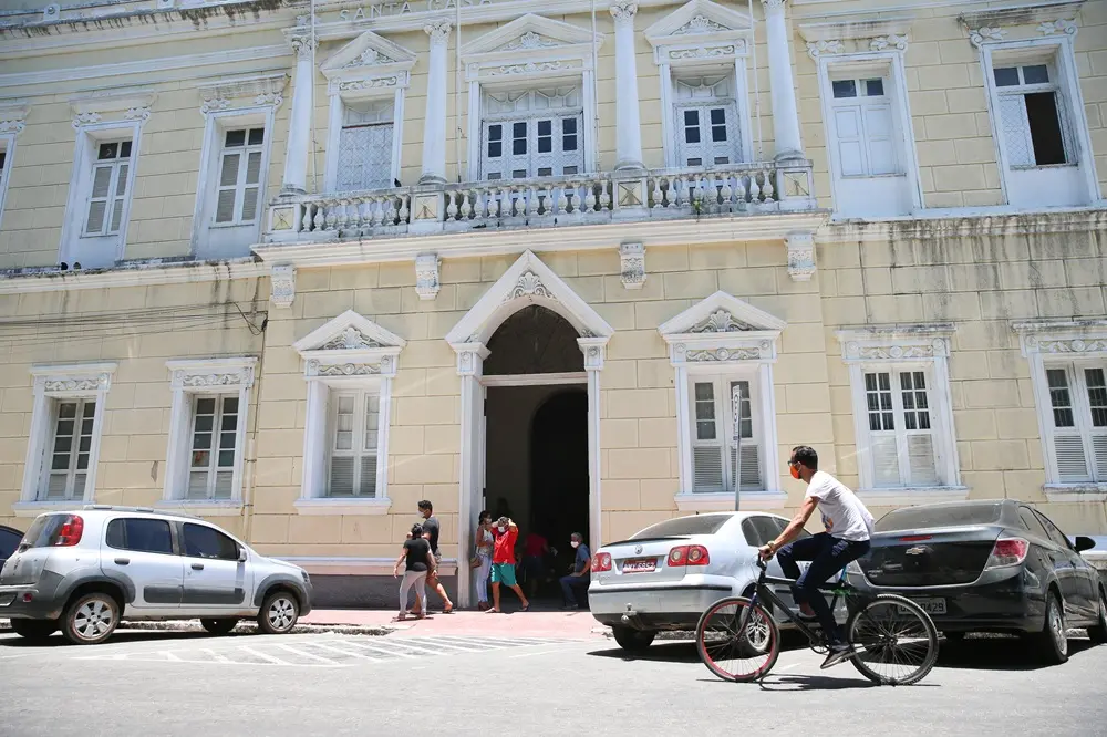 fachada da santa casa  de misericórdia de Fortaleza com carros estacionados e pessoas circulando a pé e de bicicleta