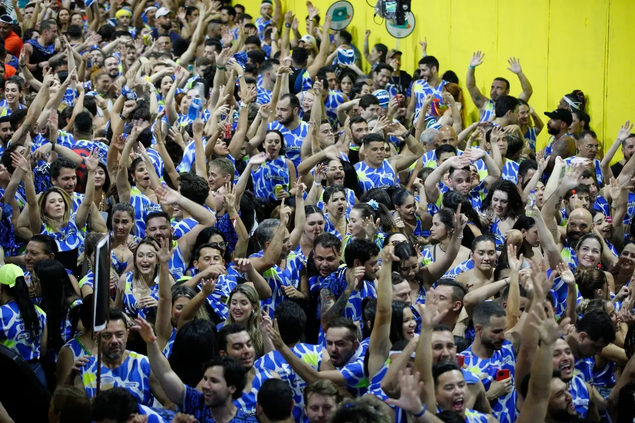 Multidão no corredor da folia do Fortal. Pessoas vestindo abadás e dançando