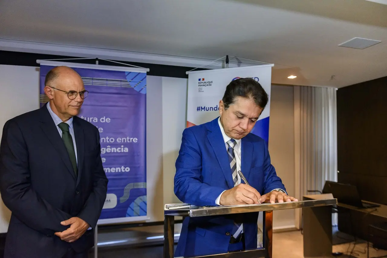 Imagem mostra presidente da Cagece, Neuri Freitas, assinando o contrato de financiamento com a Agência Francesa de Desenvolvimento. Dominique Hautbergue, diretor da AFD no Brasil, está na foto à esquerda